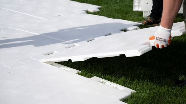 A man interlocks a piece of the flooring into another