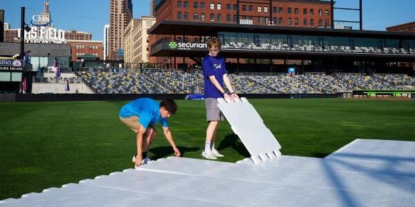 Two teenagers laying down EverBase Tiles on CHS Field