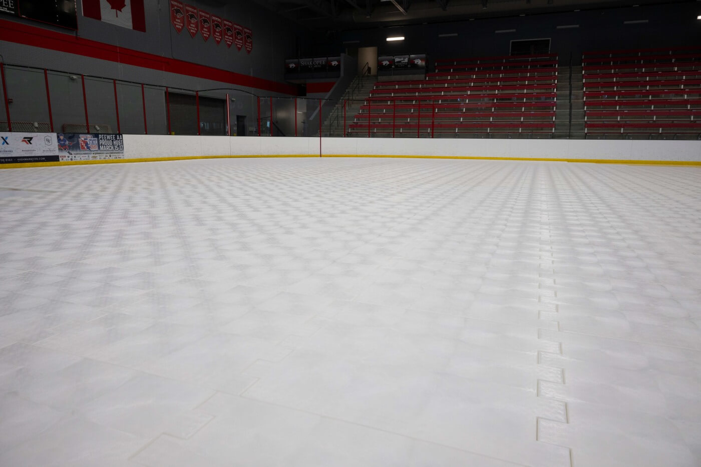 Empty indoor ice rink covered with white interlocking floor panels.