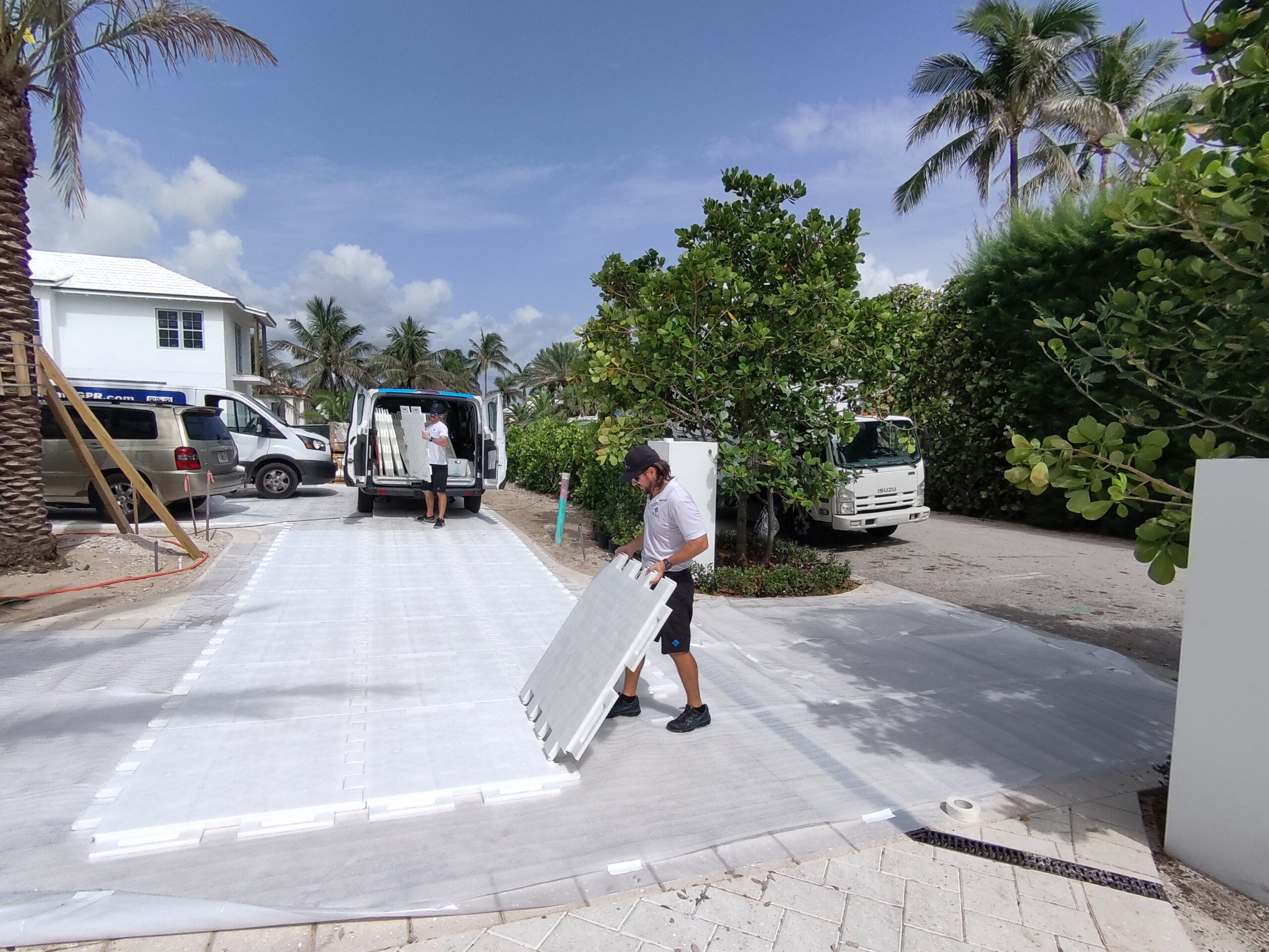A man laying modular flooring outside at luxury renovation to make a road